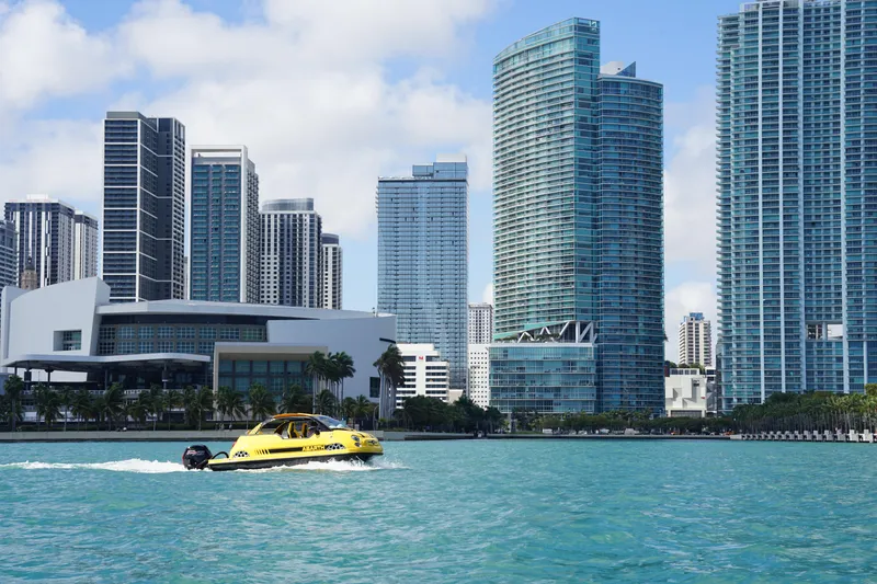 Slide: The Image of A yellow speedboat cruises near modern skyscrapers on a sunny day. - 18