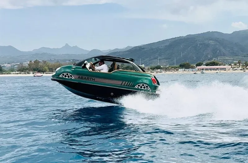 Slide: The Image of 2025 Car Off-shore Fiat 500 Abarth boat speeding on water, scenic mountain backdrop. - 26