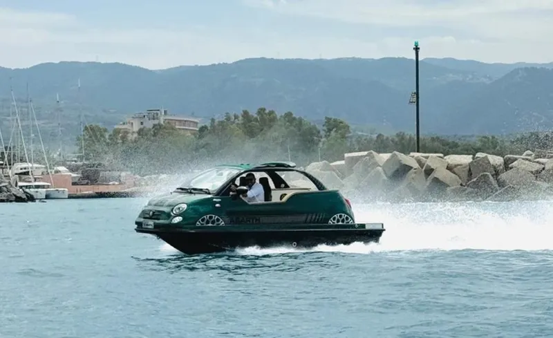 Slide: The Image of 2025 Car Off-shore Fiat 500 Abarth driving on water near rocky shoreline. - 27