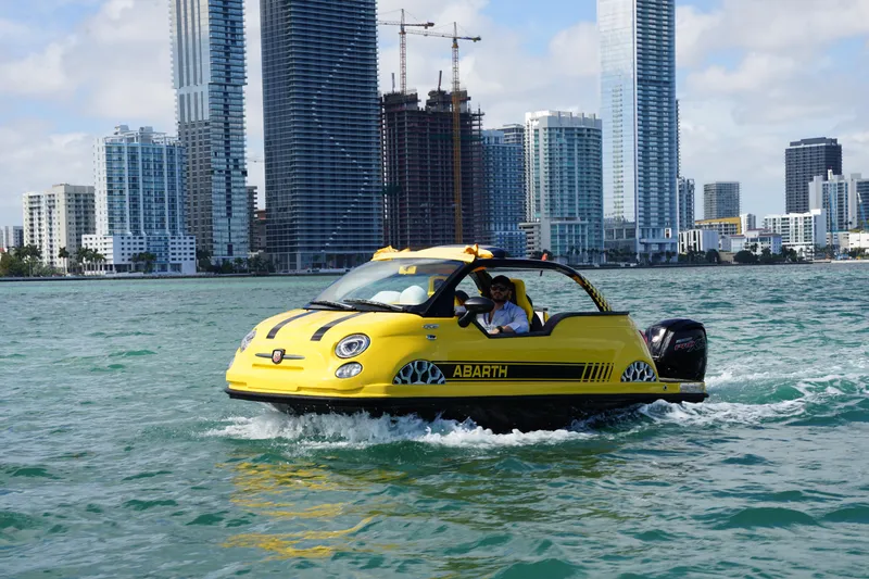 Slide: The Image of Yellow 2025 Fiat 500 Abarth boat on water, city skyline in background. - 3