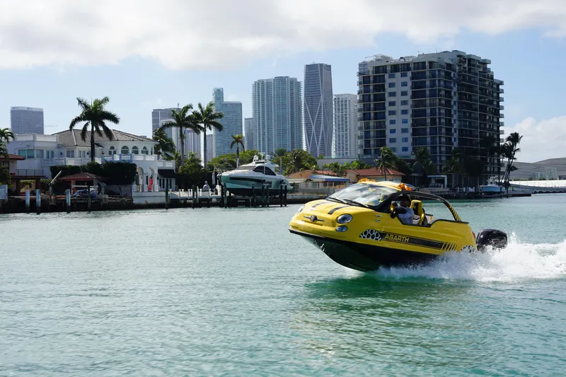 Slide: The Image of Amphibious Fiat 500 Abarth on water, city skyline in background, 2025 model. - 4