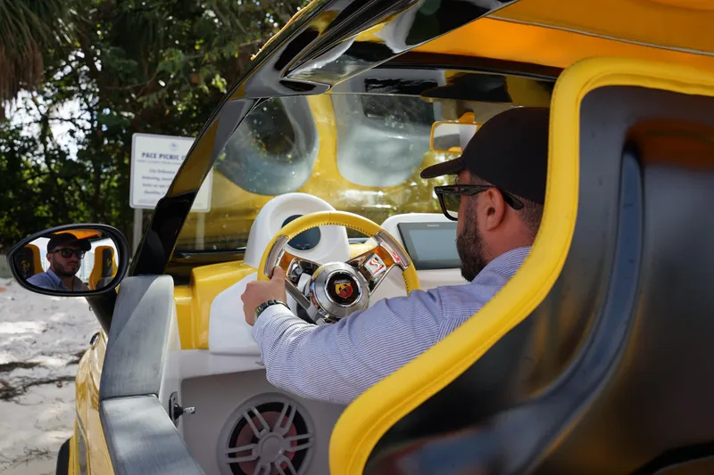 Slide: The Image of Man driving 2025 Fiat 500 Abarth with yellow interior, wearing sunglasses and cap. - 7