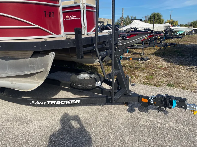 Slide: The Image of 2020 Sun Tracker Party Barge 24 DLX on trailer, parked outdoors. - 2