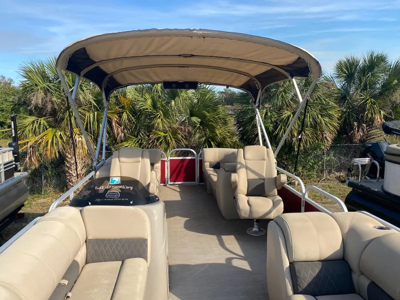 Slide: The Image of 2020 Sun Tracker Party Barge 24 DLX pontoon boat with canopy and seating, surrounded by palm trees. - 3