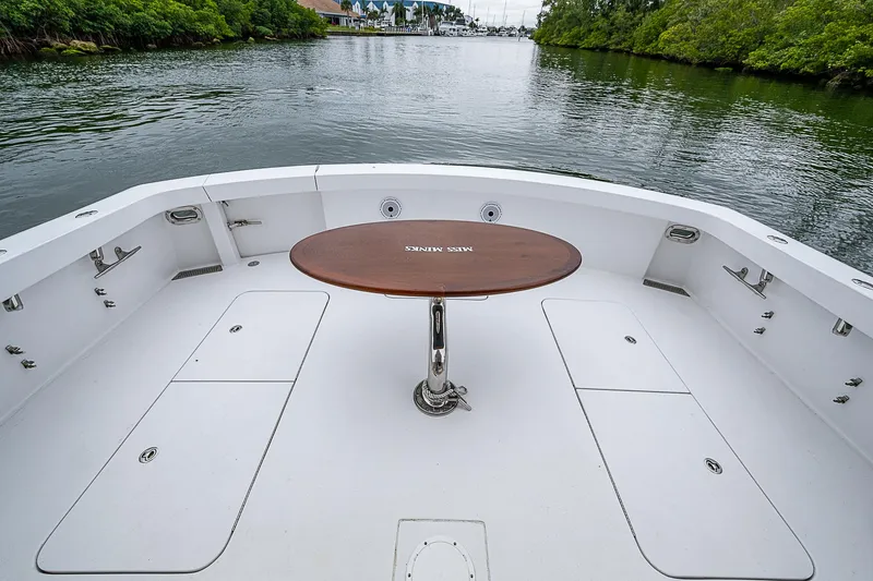 Slide: The Image of Hatteras 60 GT 2008 yacht deck with round table, surrounded by calm water and greenery. - 14