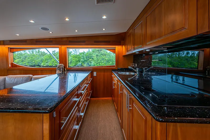 Slide: The Image of Luxurious kitchen interior of 2008 Hatteras 60 GT yacht with wood cabinetry and black countertops. - 21