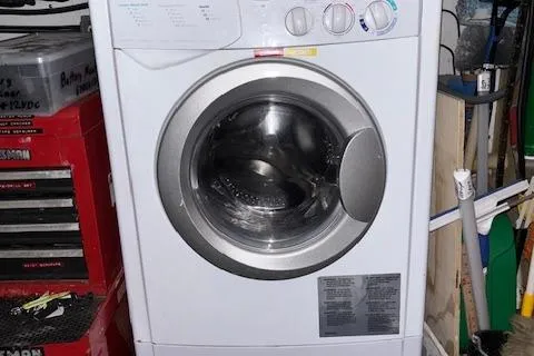 Slide: The Image of A front-loading washing machine in a cluttered utility room. - 7