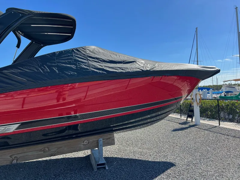 Slide: The Image of 2021 Monterey 275 Super Sport boat, red hull, covered, docked outdoors. - 2