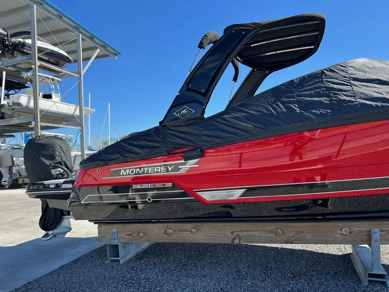 Slide: The Image of 2021 Monterey 275 Super Sport boat, red and black, covered, docked outdoors. - 3