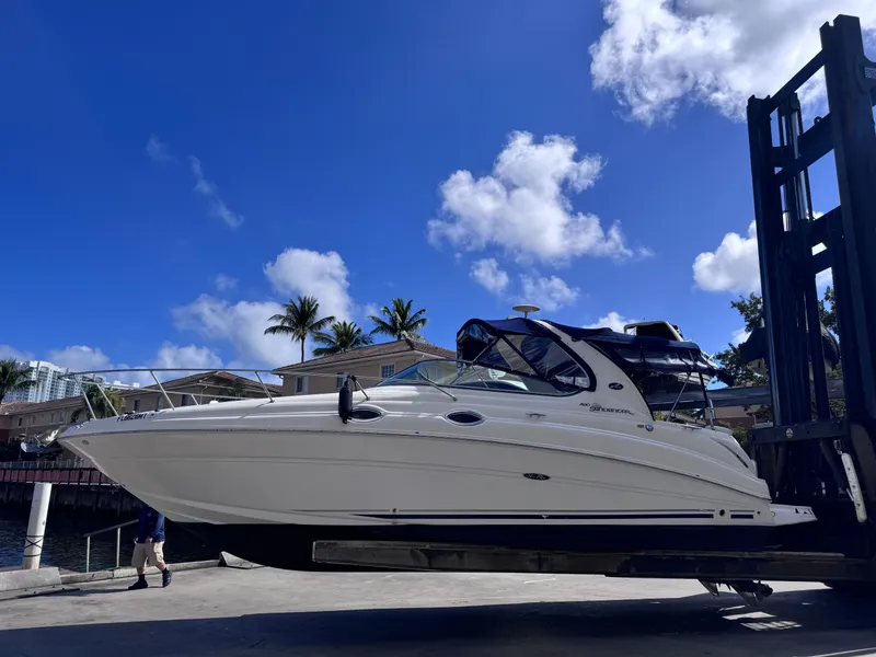 Slide: The Image of 2005 Sea Ray 280 Sundancer boat lifted by forklift under clear blue sky. - 0