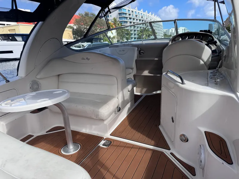 Slide: The Image of 2005 Sea Ray 280 Sundancer boat interior with seating and helm, docked in a marina. - 17