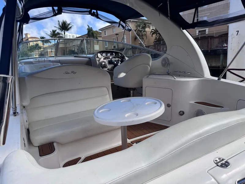 Slide: The Image of 2005 Sea Ray 280 Sundancer interior with seating and helm, docked under blue canopy. - 18