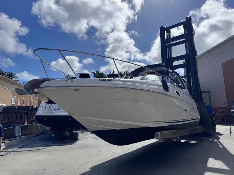 Slide: The Image of 2005 Sea Ray 280 Sundancer boat lifted by forklift under a bright blue sky. - 2