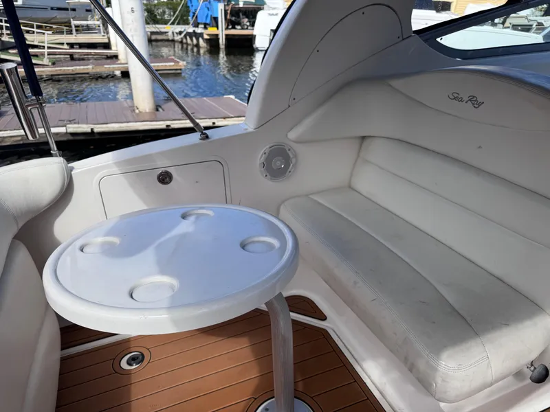 Slide: The Image of 2005 Sea Ray 280 Sundancer interior with white seating and round table, dockside view. - 21