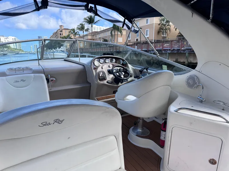 Slide: The Image of 2005 Sea Ray 280 Sundancer boat interior with helm, white seating, and waterfront view. - 22