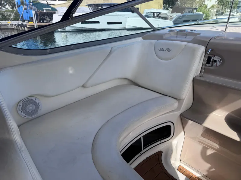 Slide: The Image of 2005 Sea Ray 280 Sundancer interior seating with white upholstery and wood accents. - 29