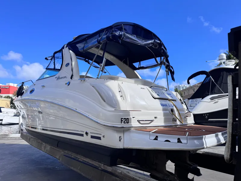 Slide: The Image of 2005 Sea Ray 280 Sundancer boat with blue canopy, docked under clear blue sky. - 3