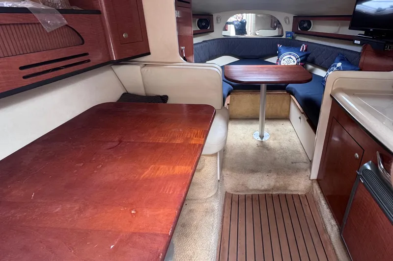 Slide: The Image of Interior of a 2005 Sea Ray 280 Sundancer boat with wooden tables and seating area. - 32
