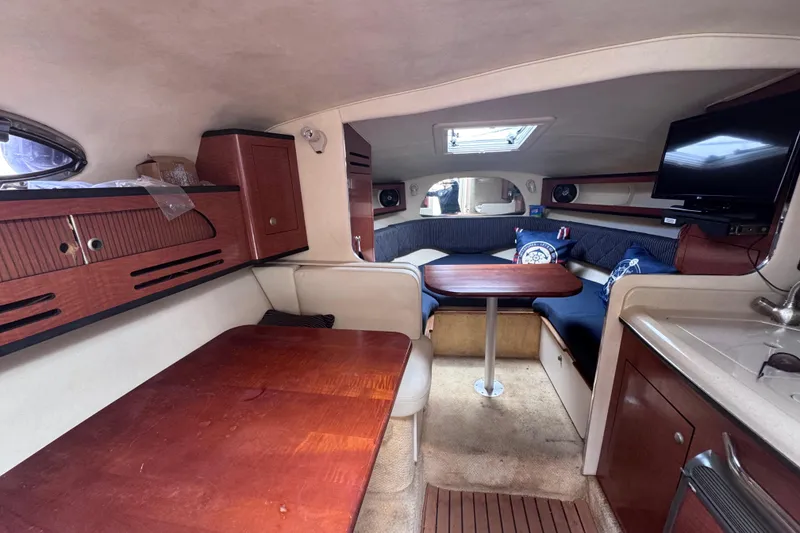 Slide: The Image of Interior of 2005 Sea Ray 280 Sundancer boat with wood furnishings and cozy seating area. - 34
