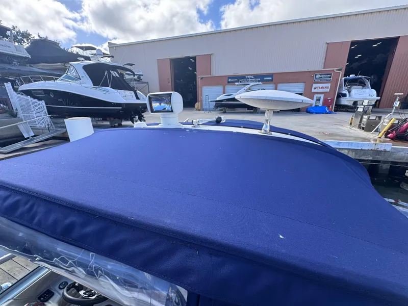 Slide: The Image of 2005 Sea Ray 280 Sundancer with blue cover docked near a marina warehouse. - 49