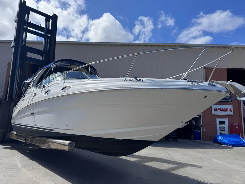 Slide: The Image of 2005 Sea Ray 280 Sundancer boat lifted at marina, clear sky background. - 7