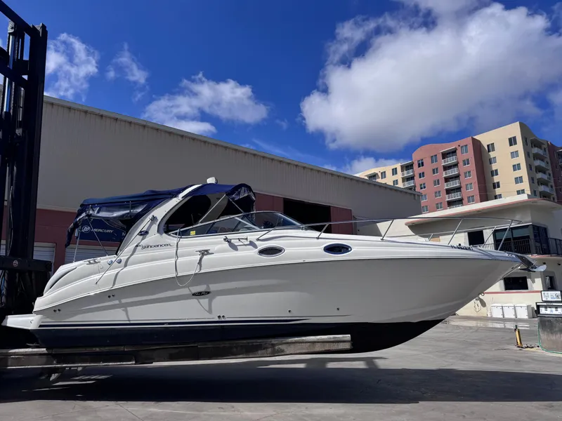 Slide: The Image of 2005 Sea Ray 280 Sundancer boat on a lift, with blue sky and buildings in the background. - 8