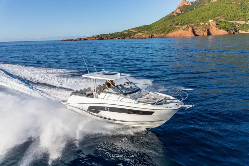 Slide: The Image of 2025 Jeanneau Leader 10.5 WA Series 2 cruising on open water near rocky coastline. - 1