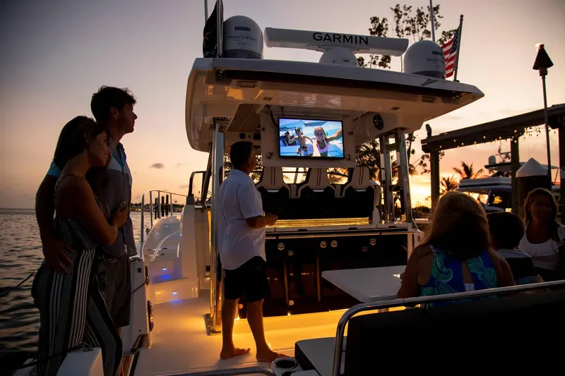 Slide: The Image of 2025 Jeanneau Leader 12.5 WA at sunset, people enjoying onboard entertainment. - 13