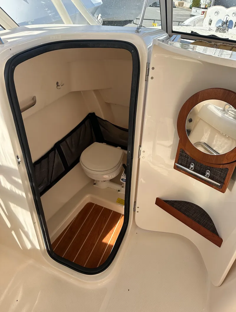Slide: The Image of 2018 Grady-White Freedom 255 boat interior with compact marine toilet and wooden accents. - 18