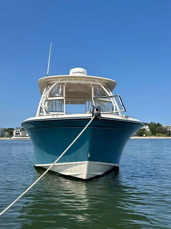 Slide: The Image of 2018 Grady-White Freedom 255 boat anchored on calm water under clear blue sky. - 2