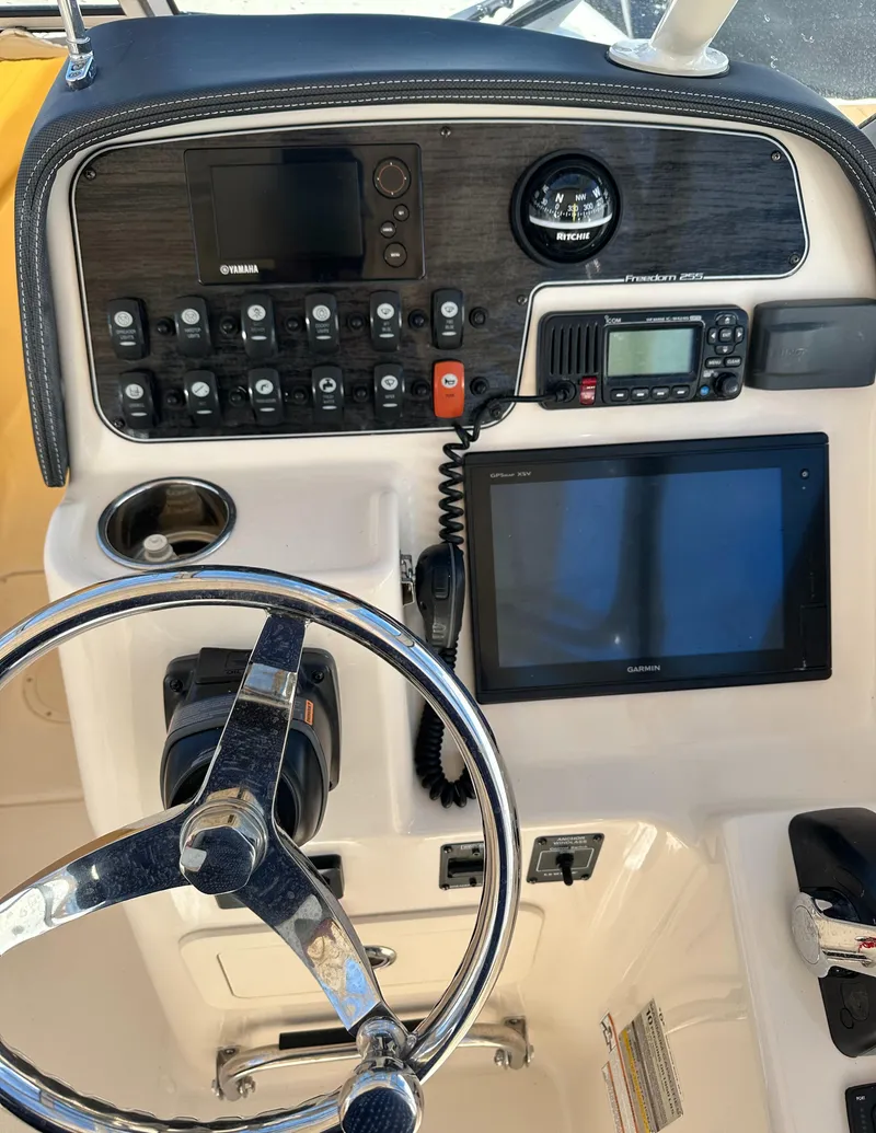 Slide: The Image of 2018 Grady-White Freedom 255 boat dashboard with steering wheel and electronic controls. - 20