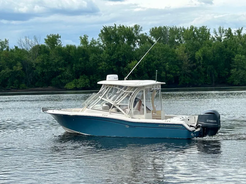 Slide: The Image of 2018 Grady-White Freedom 255 boat on calm water with lush green trees in background. - 32