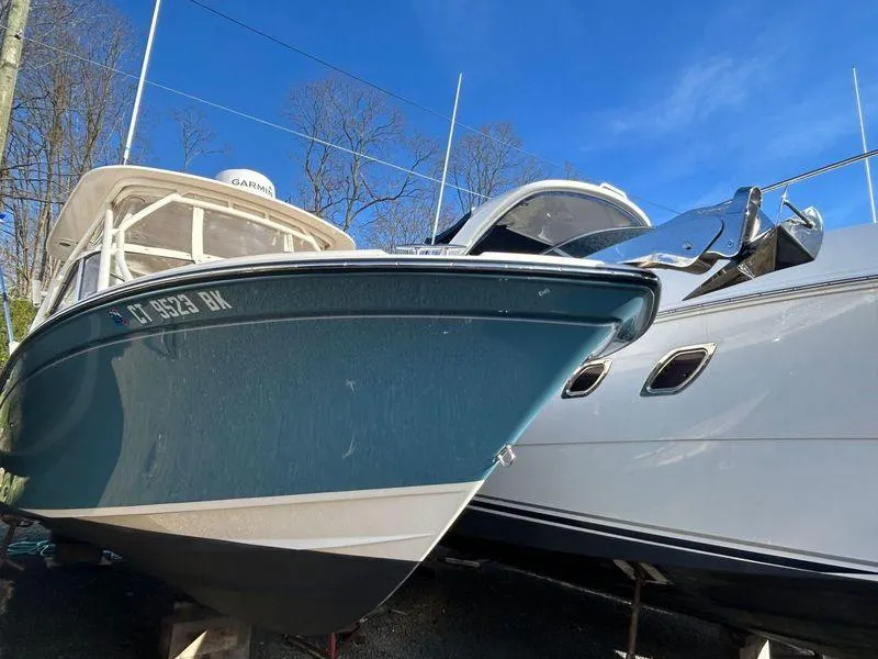 Slide: The Image of 2018 Grady-White Freedom 255 boat docked beside another vessel under clear blue sky. - 36