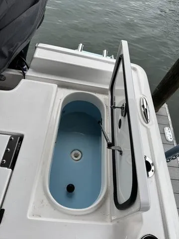 Slide: The Image of 2024 Tidewater 2300 Carolina Bay boat with open storage compartment by the water. - 11