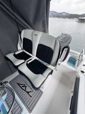 Slide: The Image of 2024 Tidewater 2300 Carolina Bay boat interior with cushioned seating by a lake. - 13