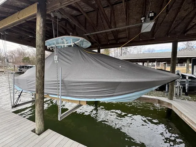 Slide: The Image of 2024 Tidewater 2300 Carolina Bay boat covered and docked under a wooden shelter. - 16