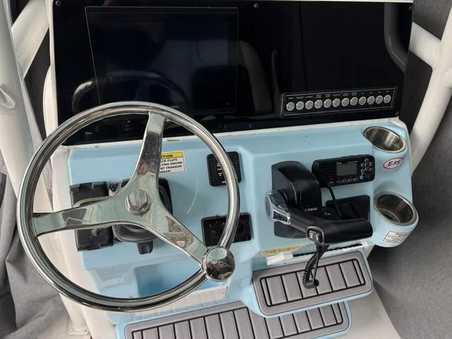 Slide: The Image of 2024 Tidewater 2300 Carolina Bay helm with steering wheel, controls, and cup holders. - 9