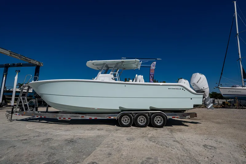 Slide: The Image of 2025 Invincible 33 Catamaran on trailer, side view, clear blue sky background. - 0