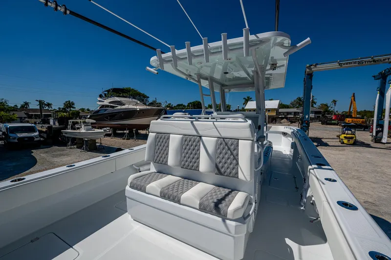 Slide: The Image of 2025 Invincible 33 Catamaran with cushioned seating and sleek design in a marina setting. - 19