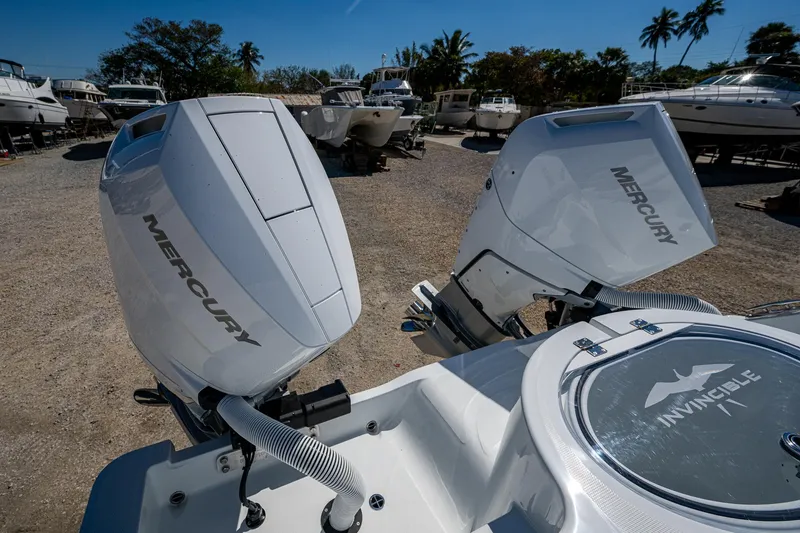 Slide: The Image of 2025 Invincible 33 Catamaran with dual Mercury outboard engines in a boatyard setting. - 21