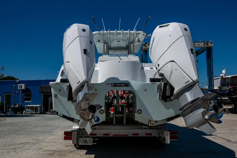 Slide: The Image of 2025 Invincible 33 Catamaran with dual outboard engines on a trailer, under clear blue sky. - 29