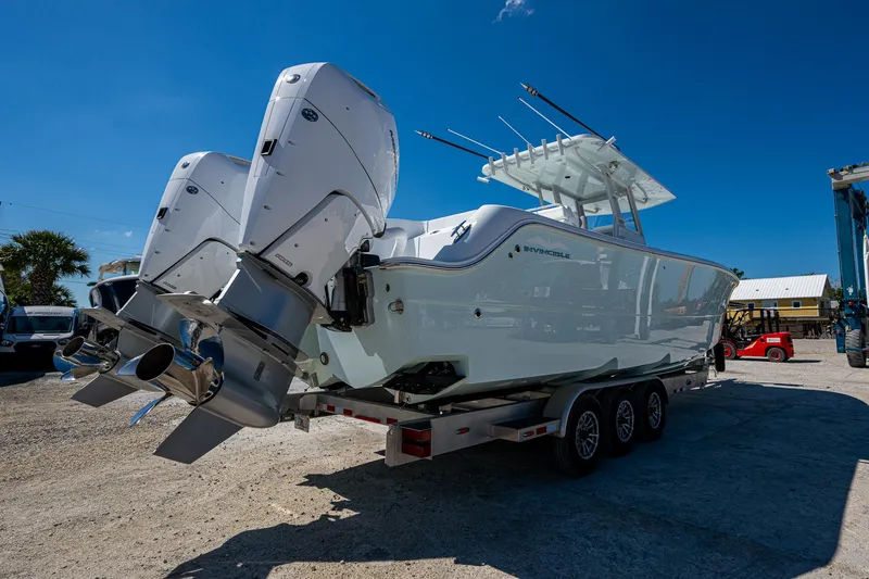 Slide: The Image of 2025 Invincible 33 Catamaran on trailer, featuring dual outboard engines, under clear blue sky. - 30