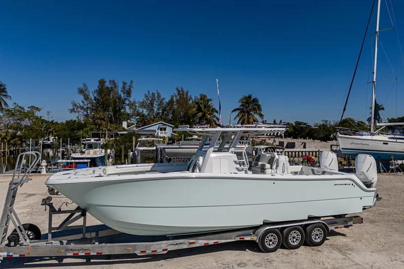 Slide: The Image of 2025 Invincible 33 Catamaran on trailer, parked outdoors with clear blue sky. - 33