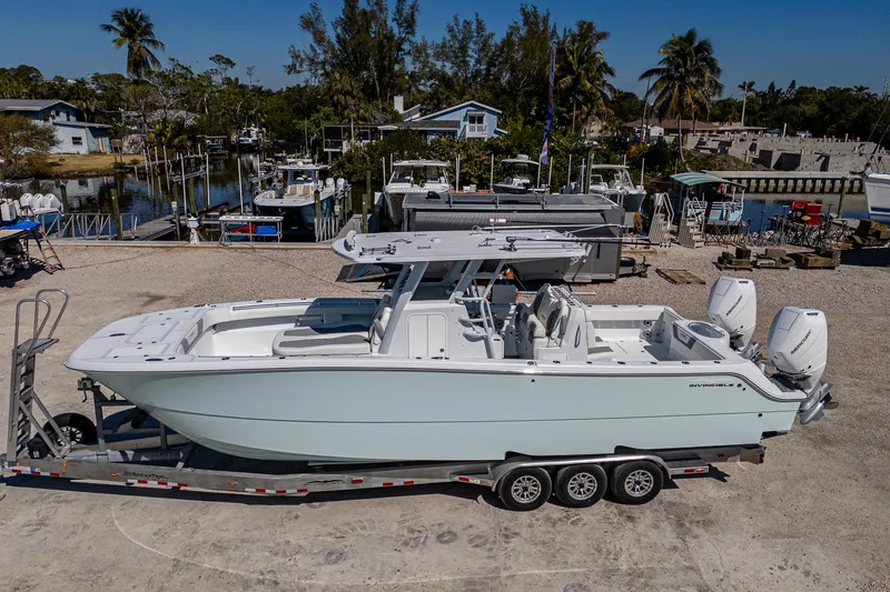 Slide: The Image of 2025 Invincible 33 Catamaran on trailer, parked near marina with palm trees in background. - 34
