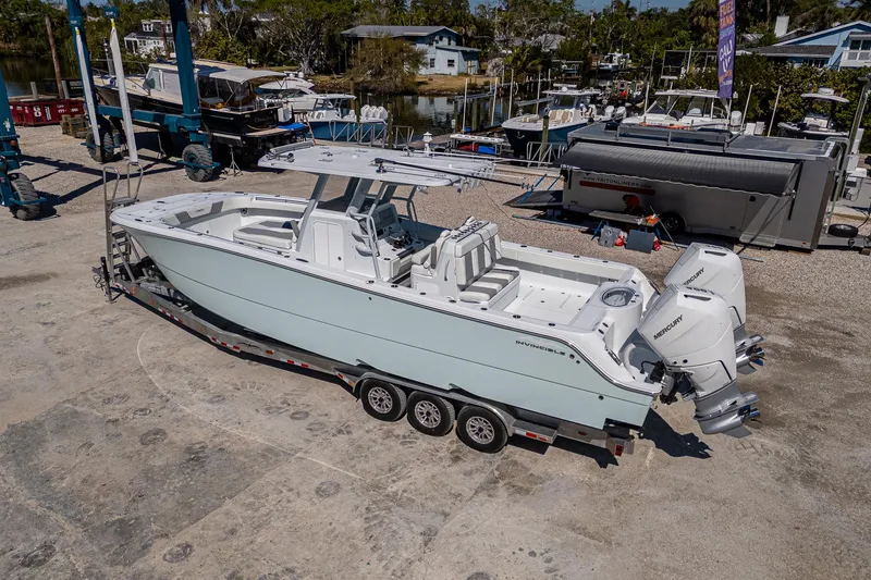 Slide: The Image of 2025 Invincible 33 Catamaran on trailer, dockside, with dual outboard engines. - 35