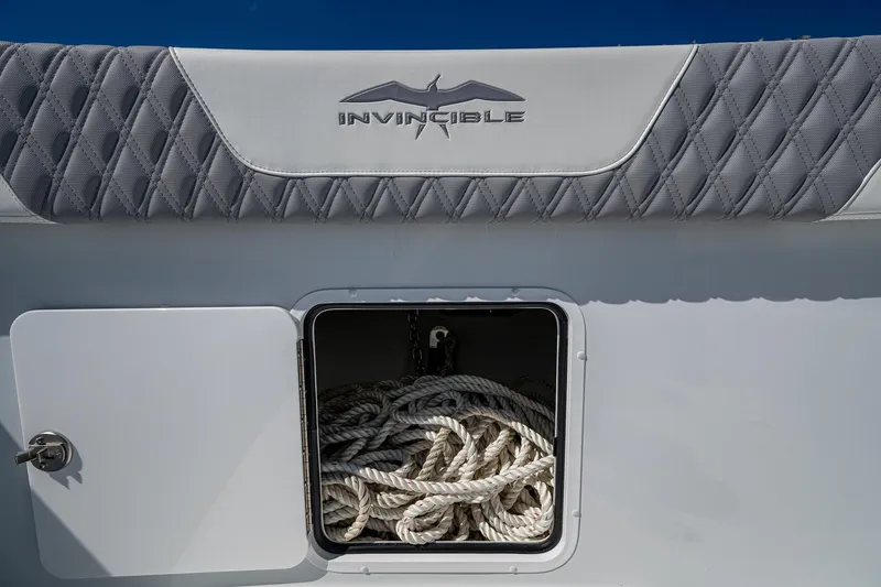 Slide: The Image of 2025 Invincible 33 Catamaran storage compartment with ropes, featuring logo and quilted upholstery. - 9