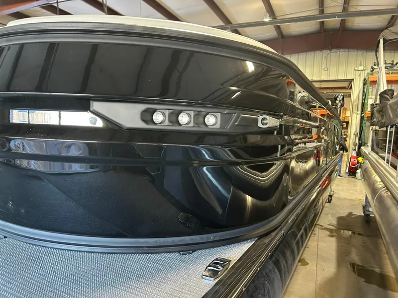 Slide: The Image of 2025 Sylvan G5 CLZ boat in a warehouse, showcasing sleek black exterior design. - 2