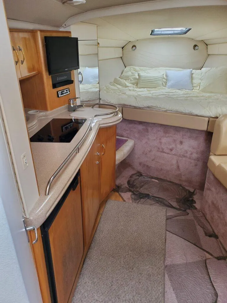 Slide: The Image of Interior of a 2000 Larson 330 CABRIO boat with kitchenette and cozy sleeping area. - 16