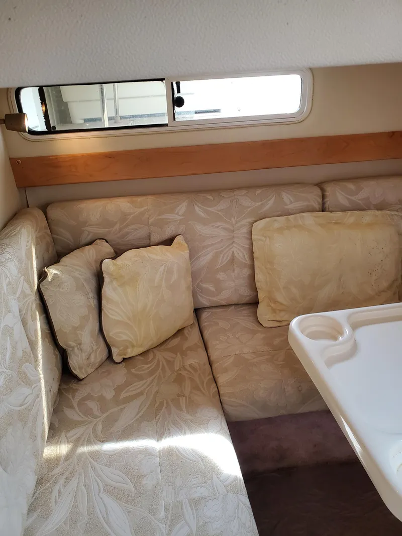 Slide: The Image of Interior of 2000 Larson 330 Cabrio boat with beige cushions and a small table. - 17