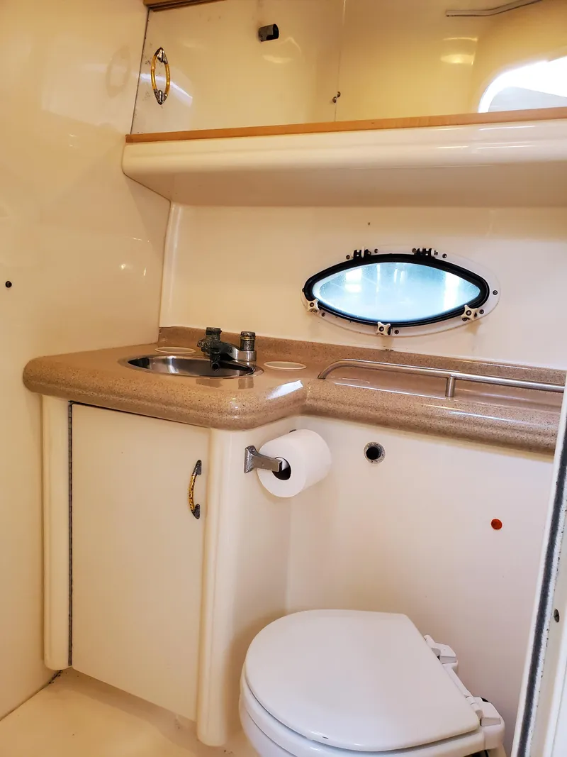 Slide: The Image of 2000 Larson 330 CABRIO boat bathroom with sink, toilet, and porthole window. - 18